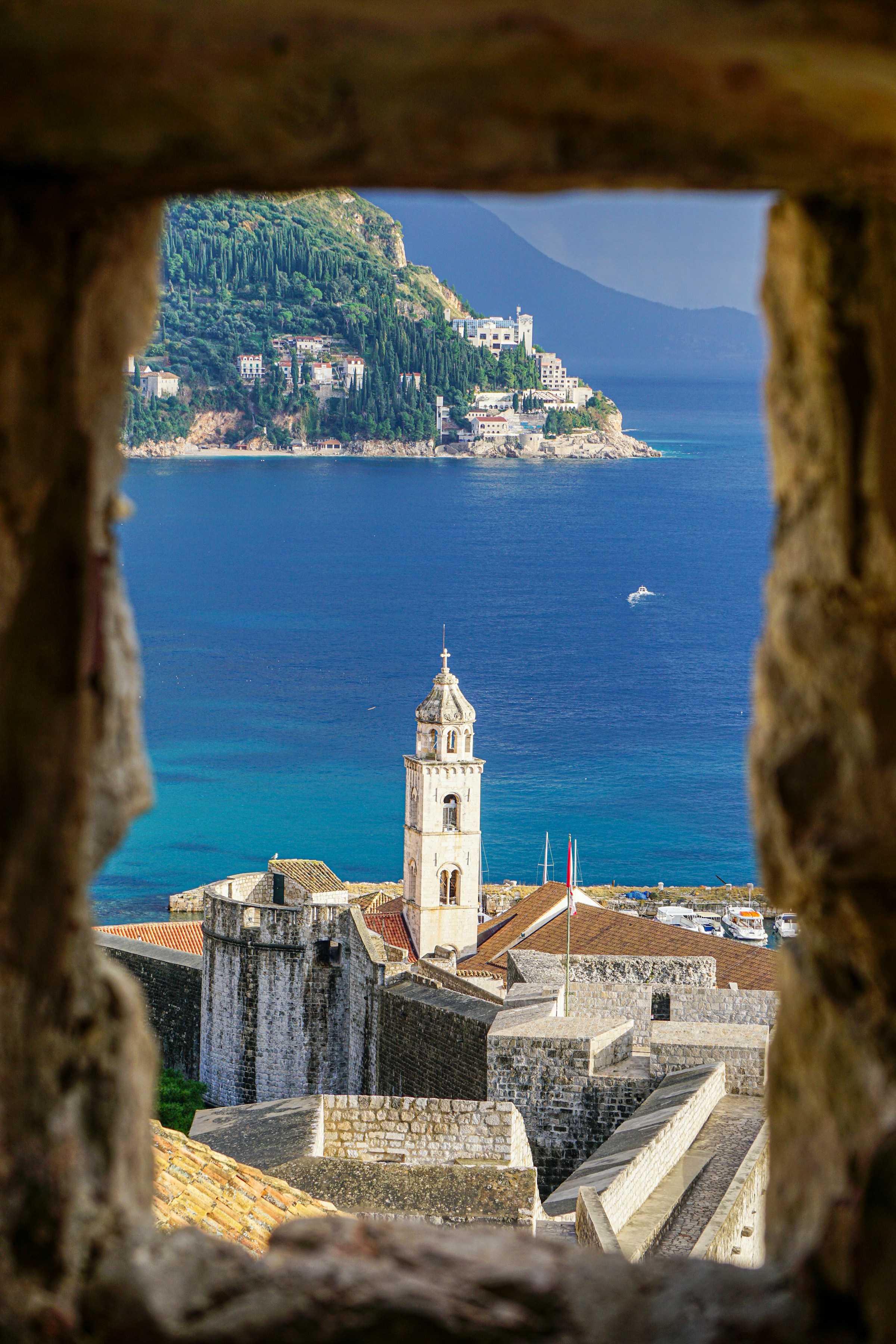 A stone bell tower and city walls overlooking the blue Adriatic Sea in Dubrovnik